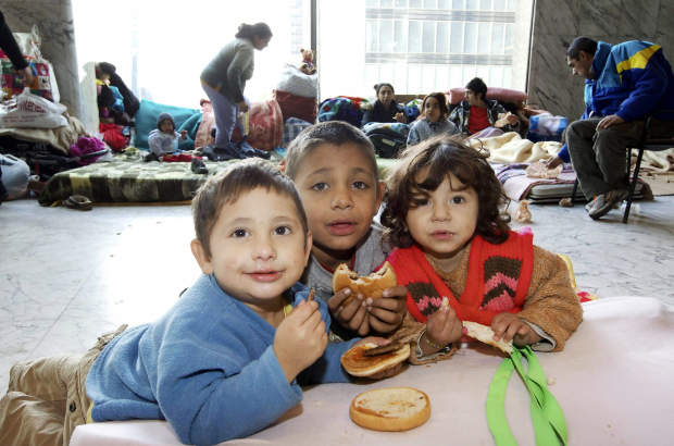 Children of the homeless refugees families who are living inside the North station in Brussels eat donated food. (BELGA PHOTO NICOLAS MAETERLINC)