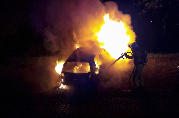 A fire officer attends to a burning car in Namur (Belga image)